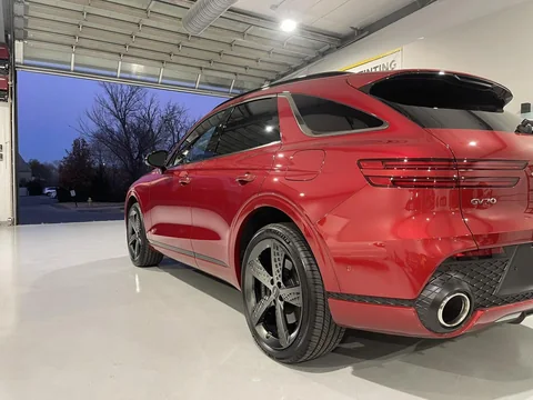 Red Genesis GV70 beside the open bay door