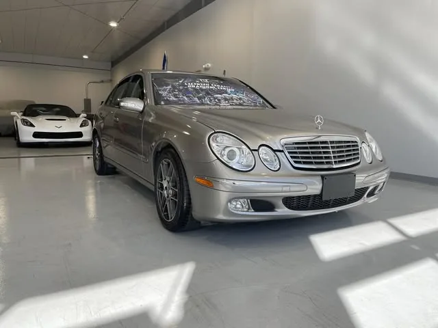 Older silver Mercedes E-Class in the shop bay